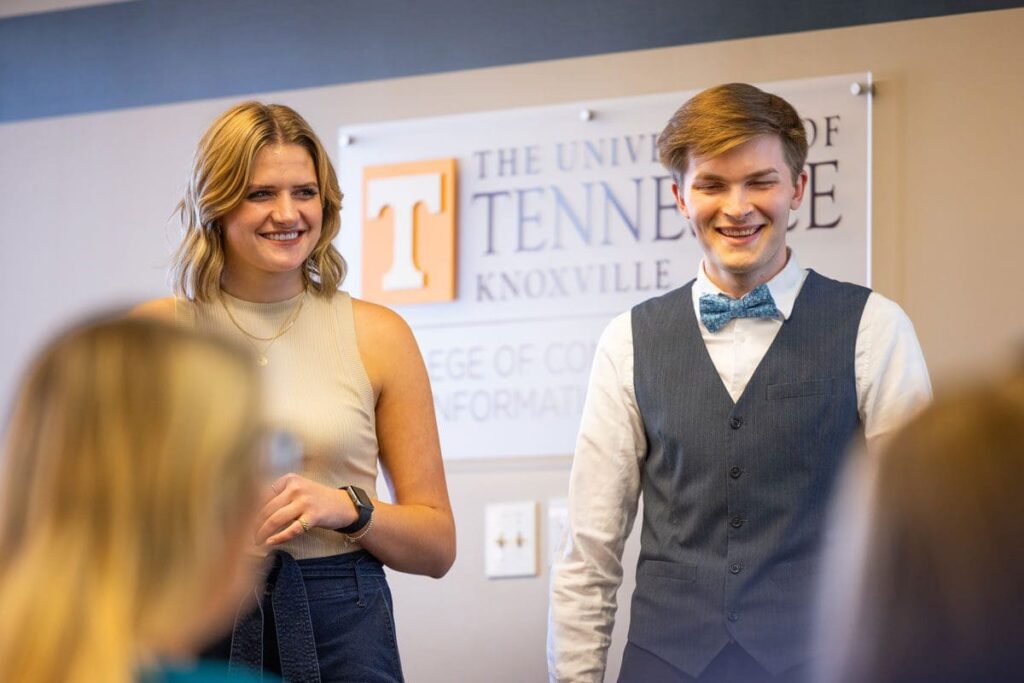 Two students smile during a presentation.